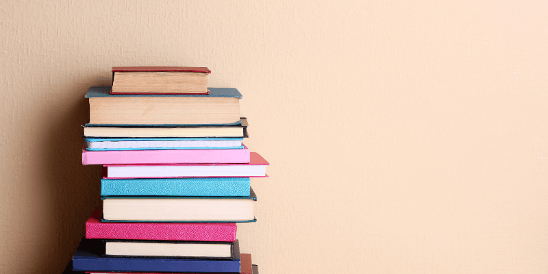 Stack of colourful books with a cream wall in the background